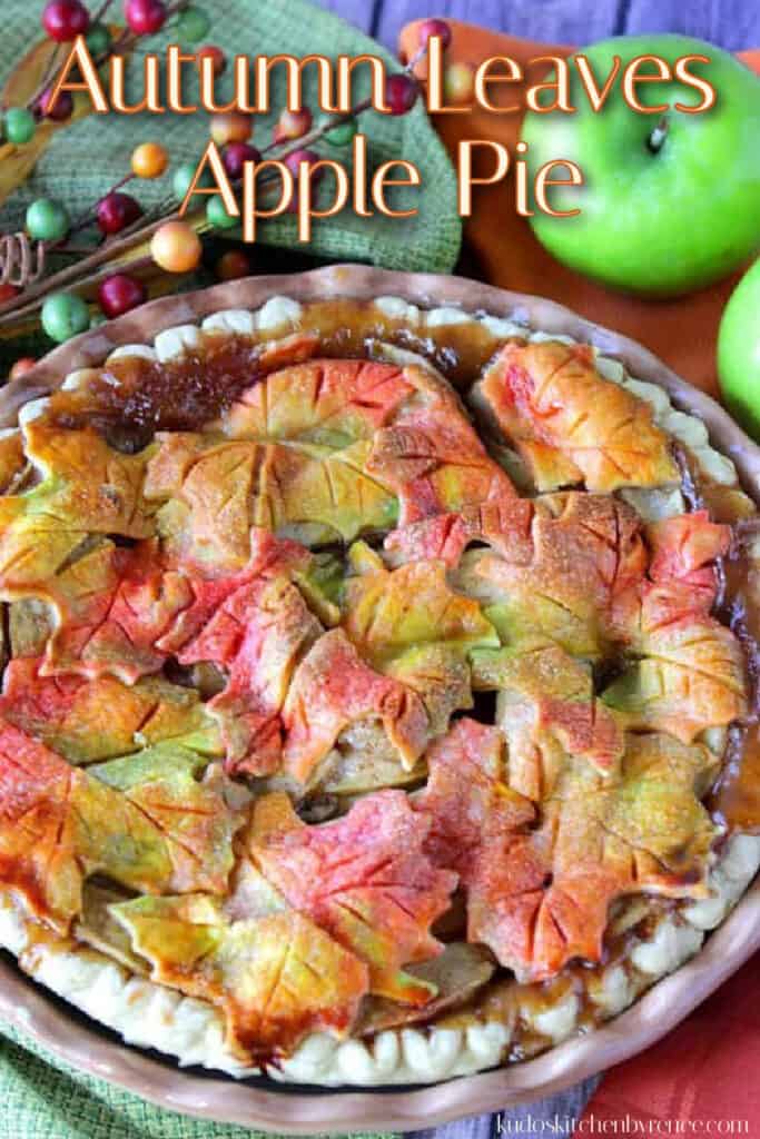A vertical closeup photo of an apple pie with colorful autumn leaves crust and a title text overlay graphic