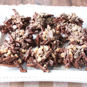 A plate filled with Chocolate Covered Shoestring Haystack cookies with toffee chips on top.