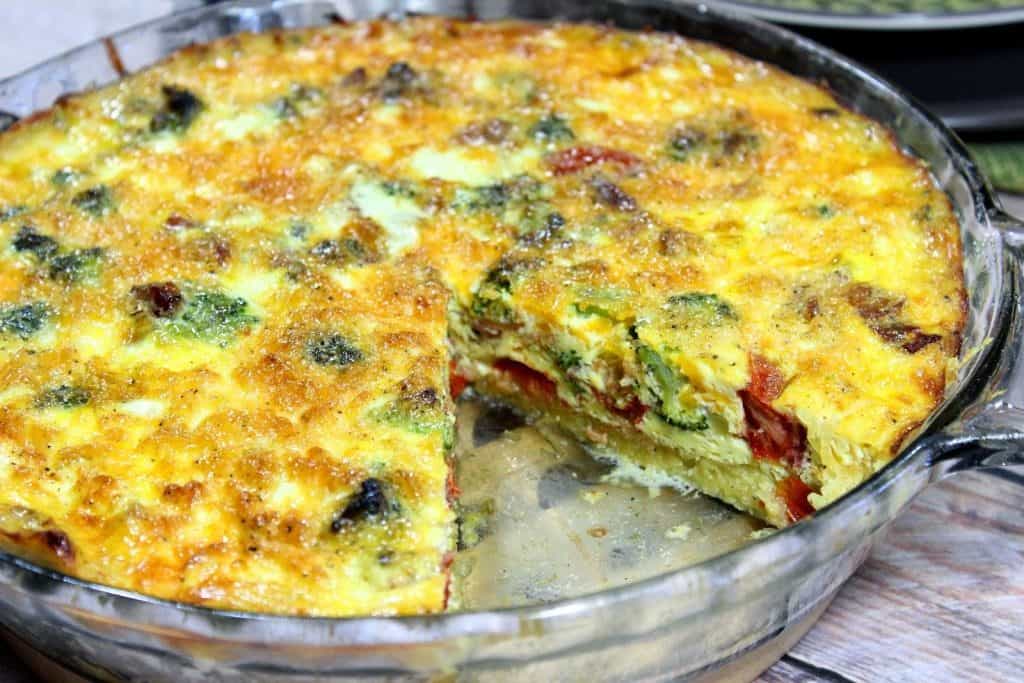 A spaghetti squash quiche in a glass pie plate with a slice taken out.