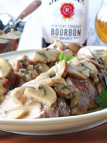 Sliced Pork Tenderloin with Mushroom Bourbon Gravy on a platter.