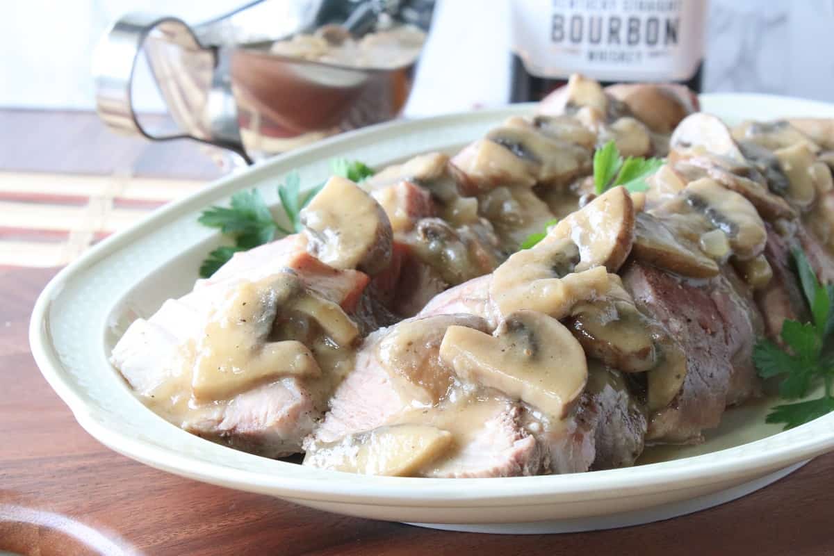 Slices of pork tenderloin on a platter with mushroom gravy.