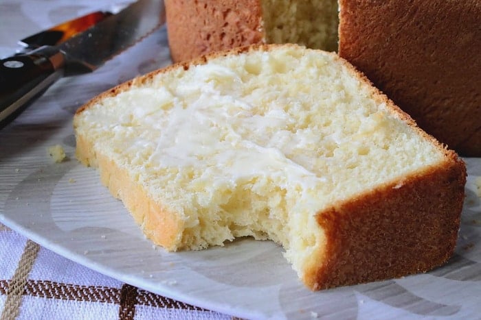 A closeup slice of a enriched batter bread with butter and bite taken out.