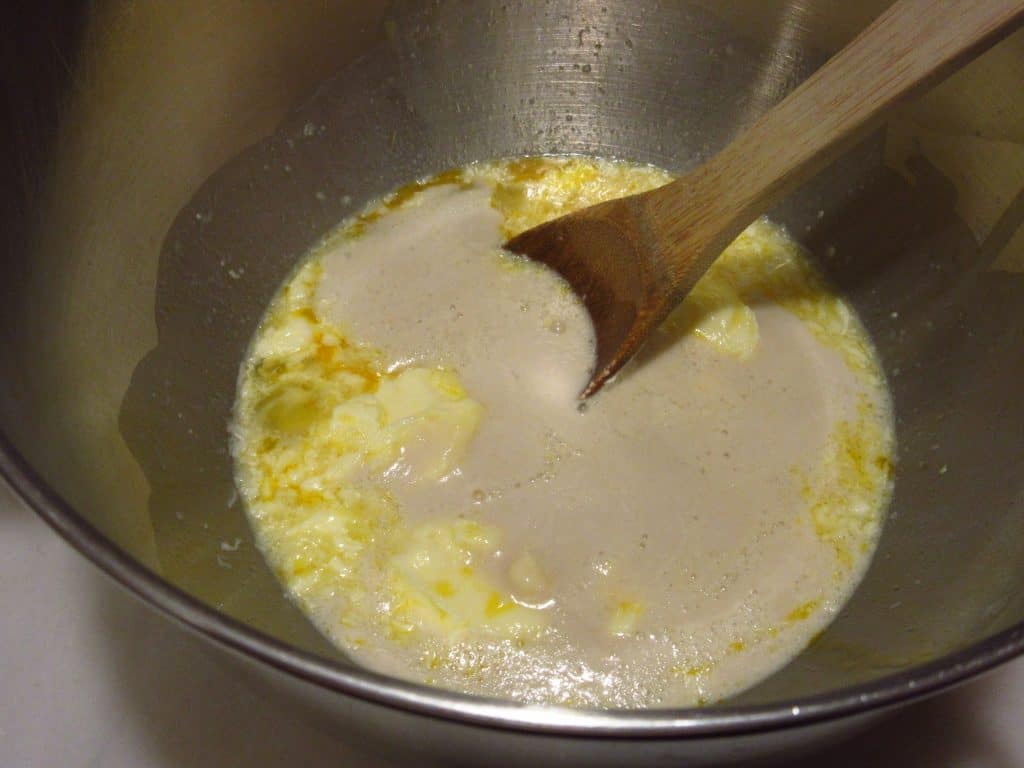 Wooden spoon in a bowl with ingredients for bread.