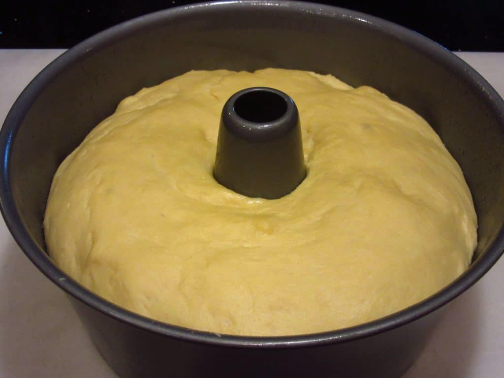 Proofed bread dough in an angel food cake pan.