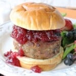 A Stuffing Stuffed Turkey Burger topped with cranberry sauce and a bun.