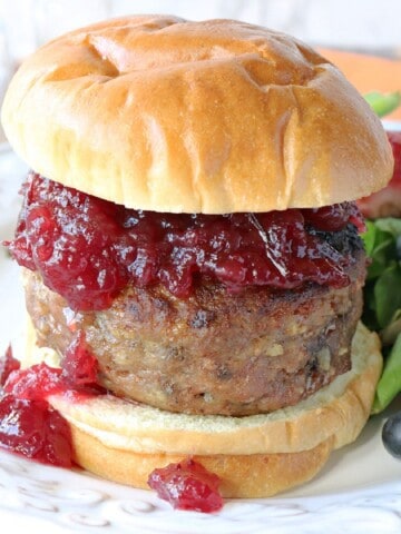A Stuffing Stuffed Turkey Burger topped with cranberry sauce and a bun.