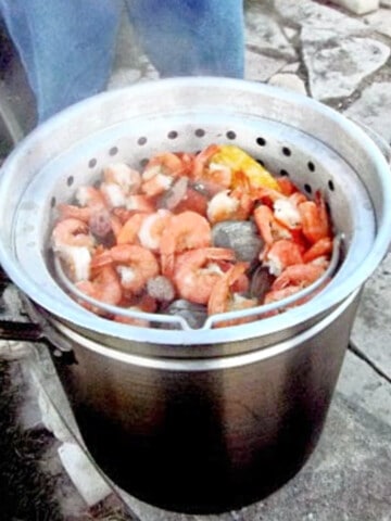 A giant pot filled with a Midwestern Low Country Boil with corn, shrimp, potatoes and sausage.