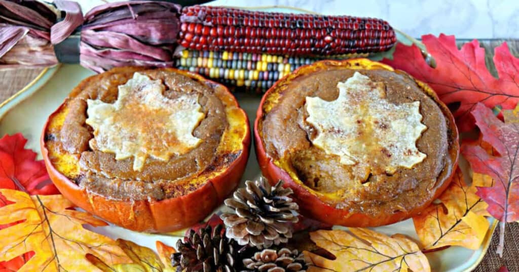 Overhead photo of two pilgrim pumpkin pies with indian corn and autumn leaves