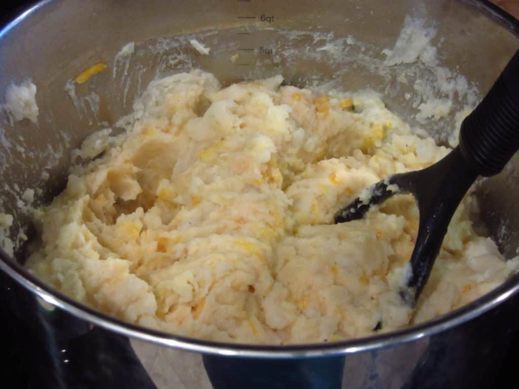 A potato masher in a pot of potatoes.