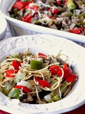 A bowl filled with Christmas Pasta in the forefront and a casserole dish filled with Christmas Pasta with Sausage in the background.