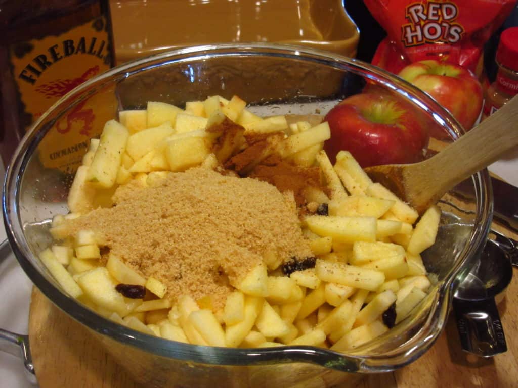 Brown sugar in a bowl of diced apples.