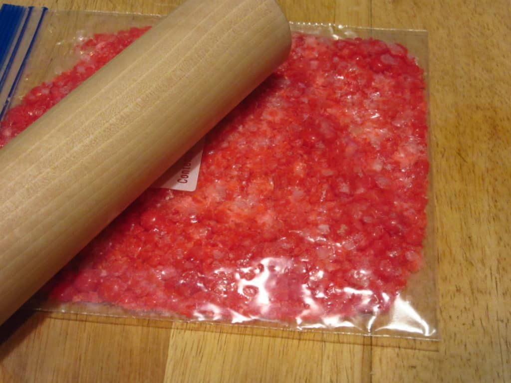 Red hot candy being smashed in a plastic bag.