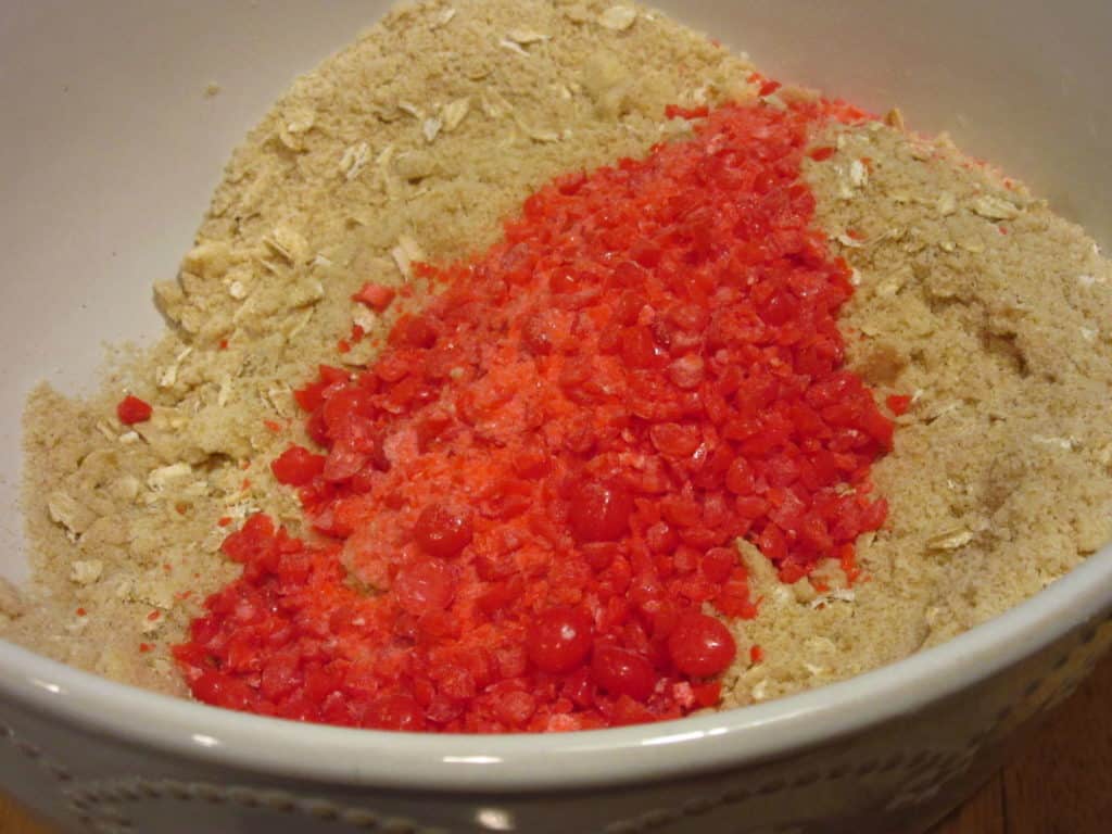 Smashed red hot candy being added to a bowl with topping.