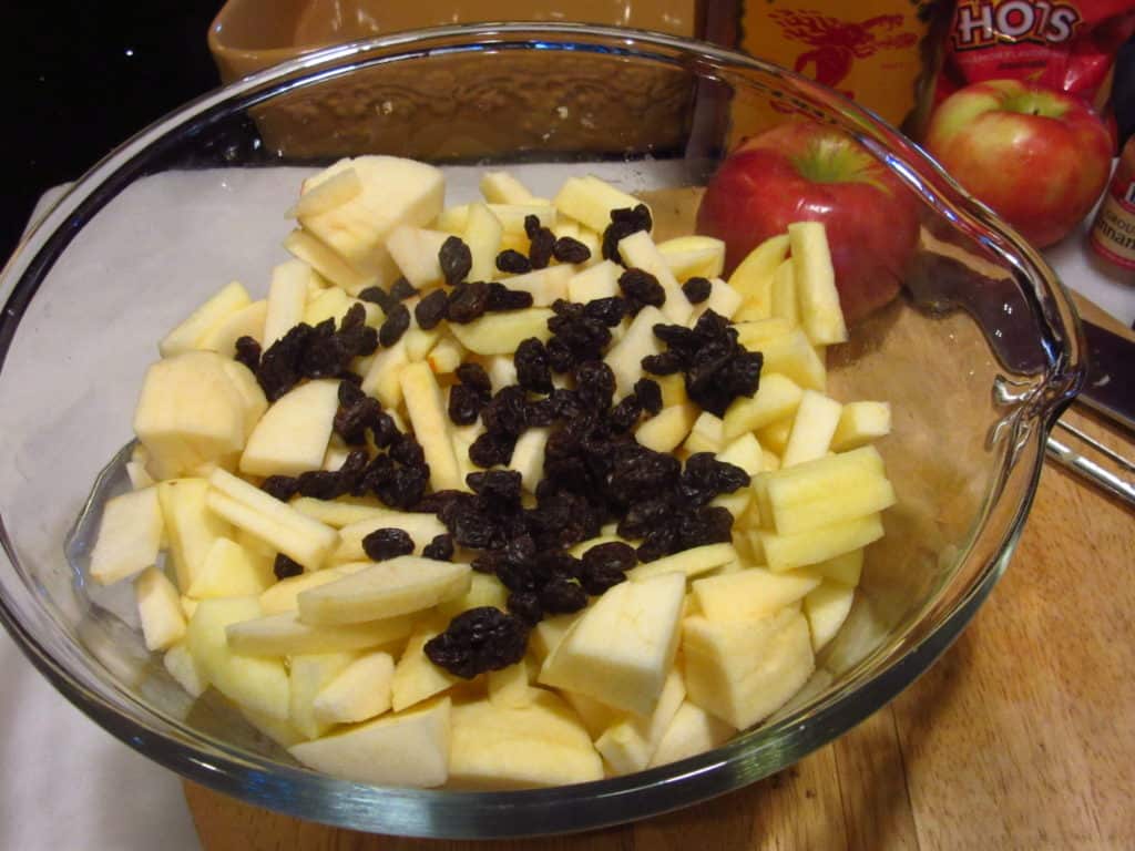 Apples and dried cranberried in a blass bowl.