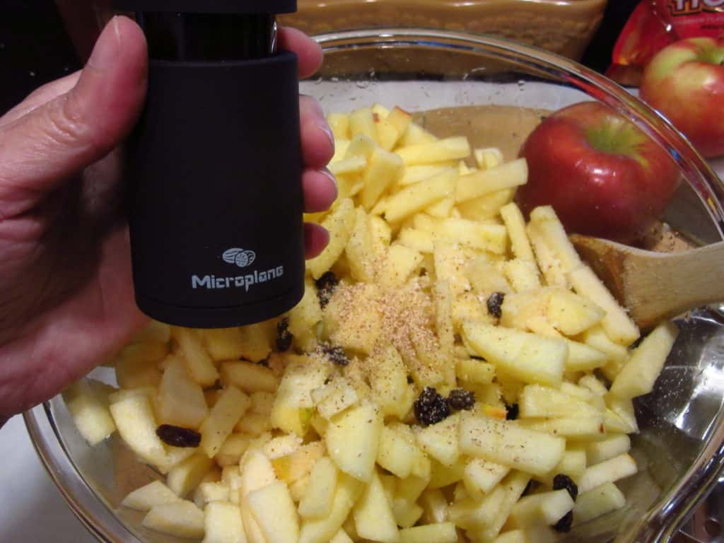 A nutmeg grater over a bowl of diced apples.
