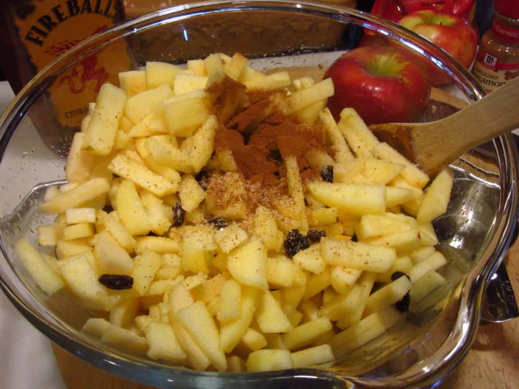 Cinnamon in a bowl of diced apples.