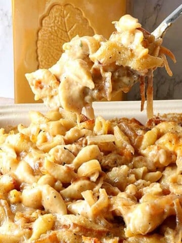 A spoon full of French Onion Mac and Cheese being served.