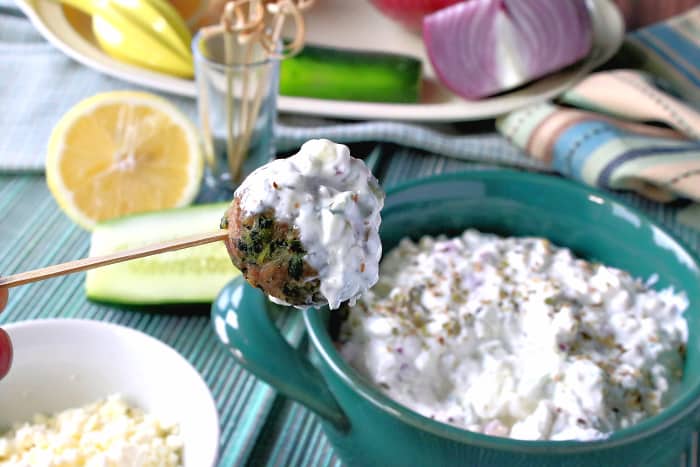 A Greek meatball on a toothpick with tzatziki sauce, lemon, oregano, and cucumber dip.