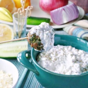 A Greek Meatball Appetizer on a skewer and covered with tzatziki sauce.