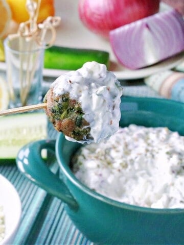 A Greek Meatball Appetizer on a skewer and covered with tzatziki sauce.