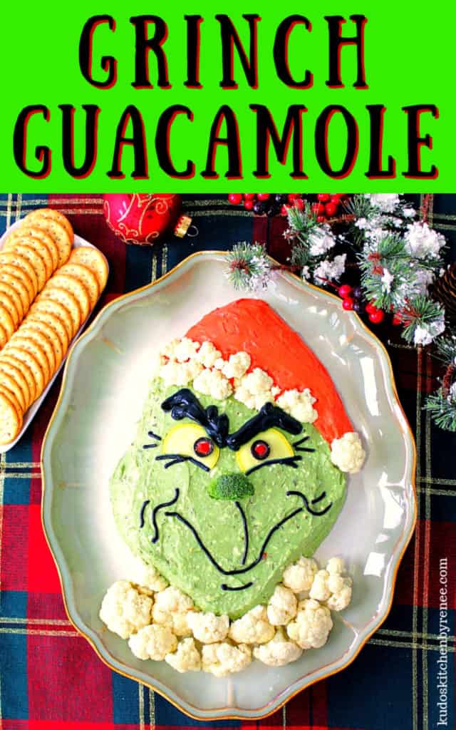 Highly saturated vertical title text image of Grinch guacamole with crackers and Christmas ornaments on a plaid tablecloth.