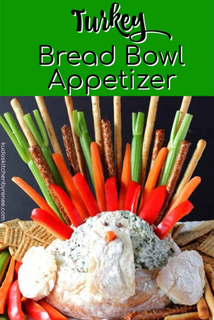 A colorful Turkey Bread Bowl Appetizer filled with spinach dip and colorful tailfeathers for dipping.
