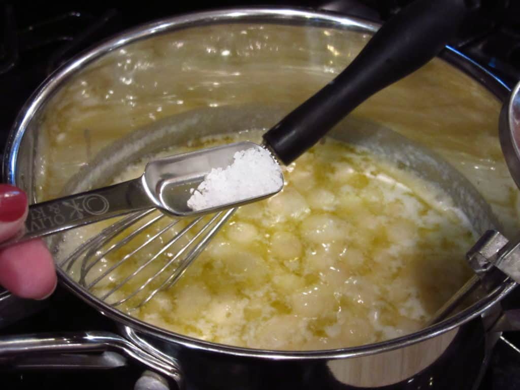 Salt being added to a boiling mixture in a saucepan.