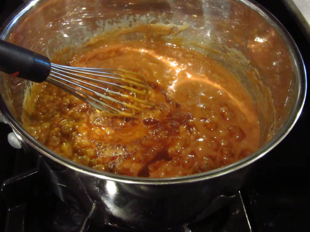 A whisk in a saucepan with toffee.