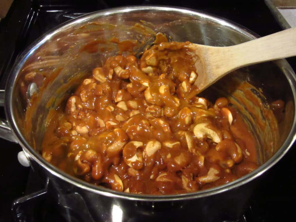 A wooden spoon in a saucepan with cashew toffee.