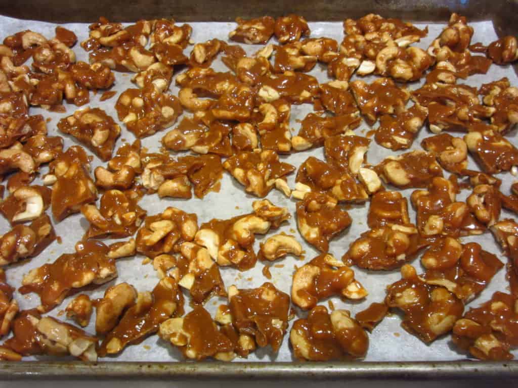 Cashew Toffee in pieces on a baking sheet.