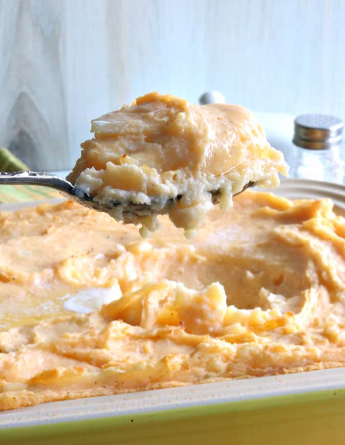 Vertical closeup image of a serving spoon filled with make-ahead cheesy horseradish mashed potato side dish.