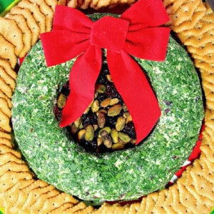 A festive Goat Cheese Christmas Wreath Appetizer with parsley, pistachios and crackers.