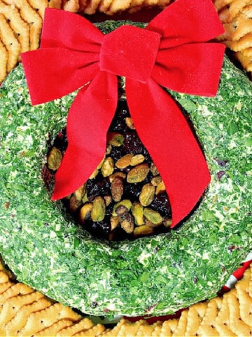A festive Goat Cheese Christmas Wreath Appetizer with parsley, pistachios and crackers.
