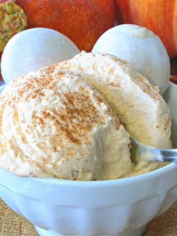 A scoop of Pumpkin Pie Ice Cream in a white bowl with a spoon.