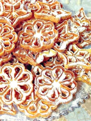 A stack of Fried Rosette Snowflake Cookies with icing sugar on top.