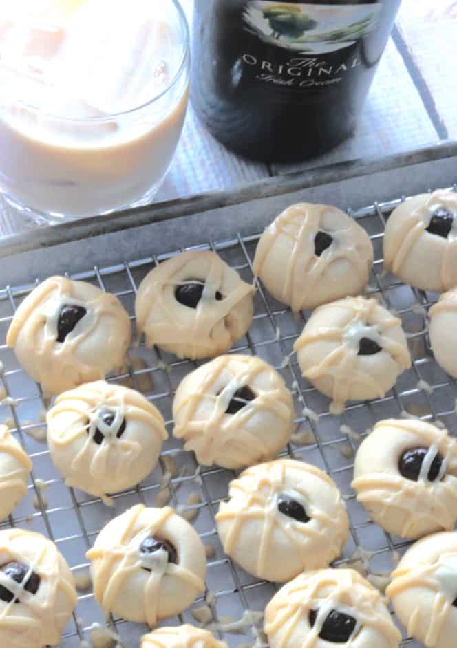 A vertical overhead photo of a baking sheet with a rack filled with Irish cream cookies topped with a glaze and a espresso bean.