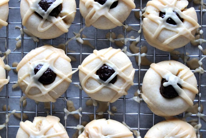 Overhead closeup photo of cookies on a baking rack drizzled with glaze and a chocolate covered espresso bean.