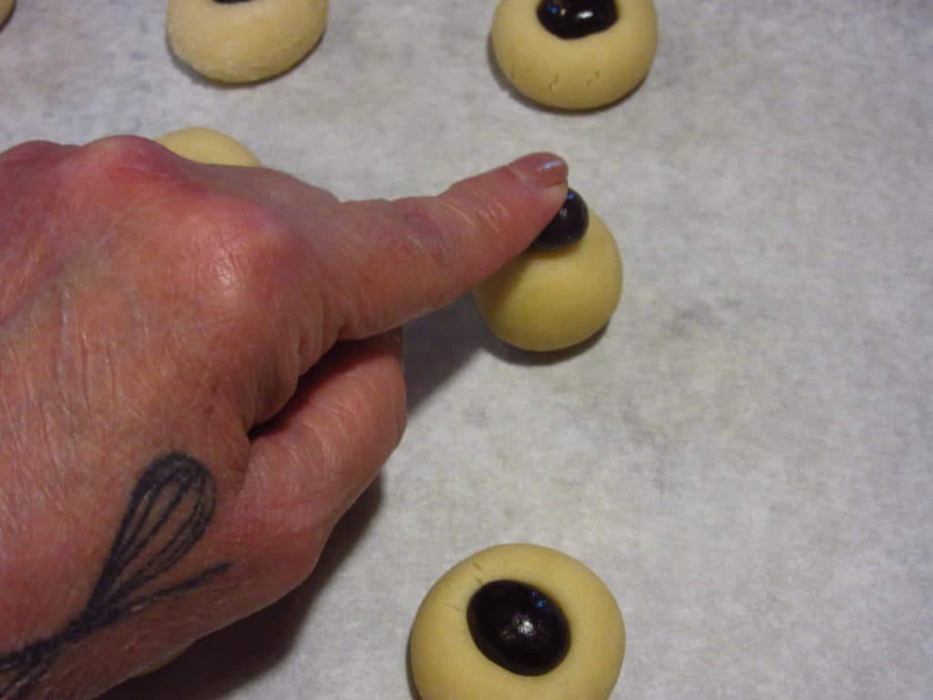 A hand pressing a expresso bean in the top of a dough ball.