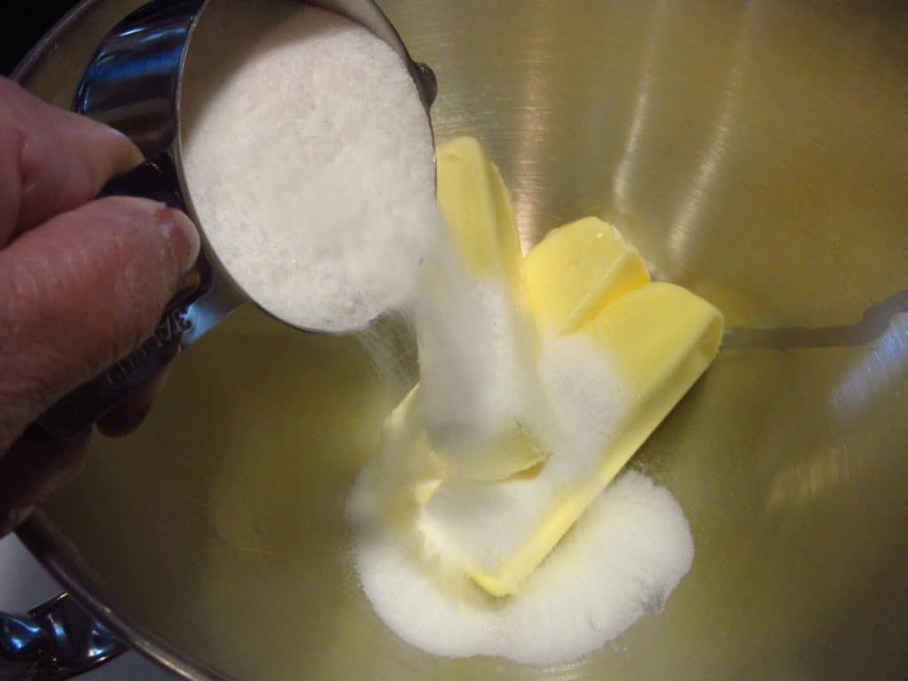 Sugar being poured into a bowl with butter.