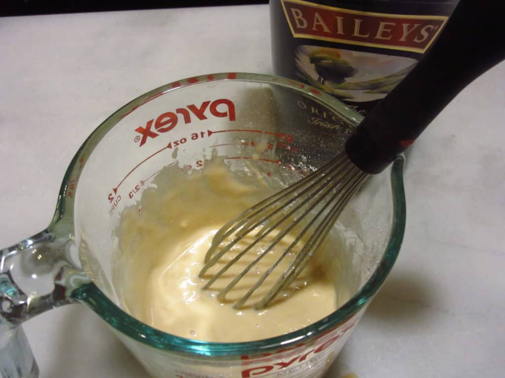 Icing in a glass measuring cup with a whisk.