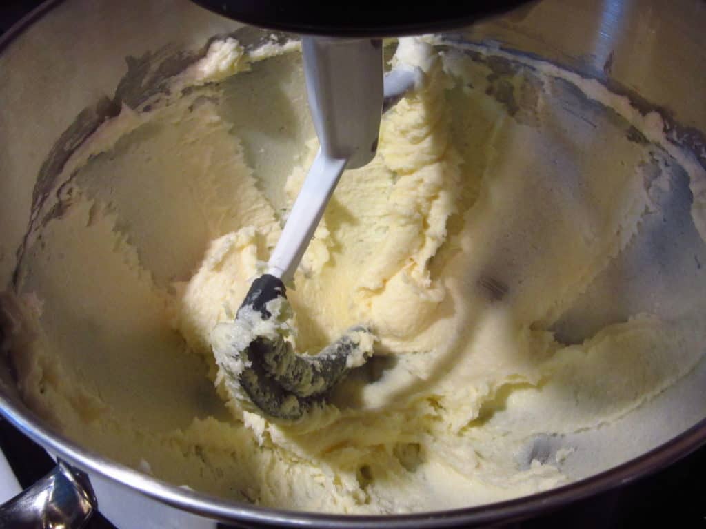 A paddle attachment in a stand mixer with butter and sugar.