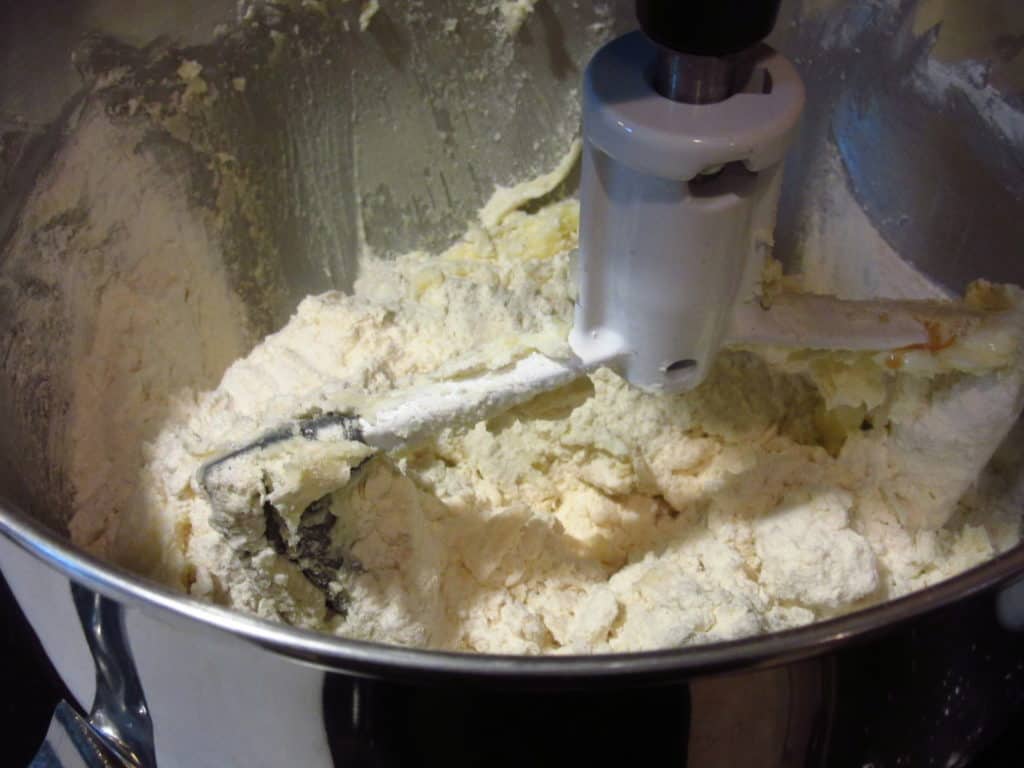 A paddle attachment in a stand mixer mixing cookie dough.