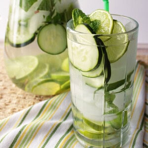 A refreshing glass of cucumber lime fitness water with ice and cucumber slices.