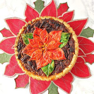 A Bourbon Pecan Pie with a poinsettia crust on a poinsettia placemat.