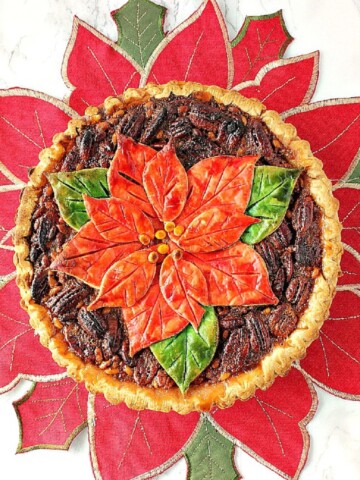 A Bourbon Pecan Pie with a poinsettia crust on a poinsettia placemat.