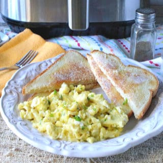 A plate of air fryer scrambled eggs with toast and a salt and pepper shaker in the background.