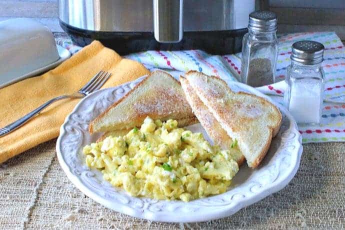 A plate of air fryer scrambled eggs with toast and a salt and pepper shaker in the background.