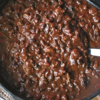 An overhead photo of molé turkey chili in a cast iron Dutch oven with a serving spoon