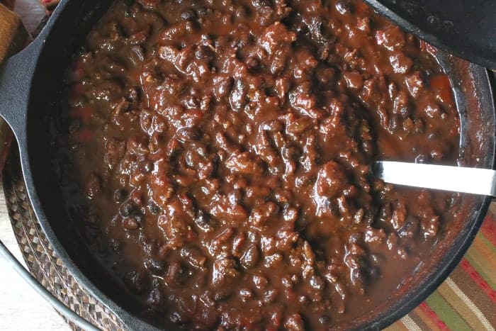 An overhead closeup horizontal photo looking inside a cast iron pot of turkey chili with beans, chorizo, and tomatoes.