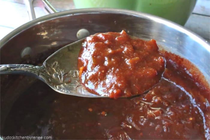 A closeup horizontal photo of salsa bbq sauce on a decorative silver spoon.